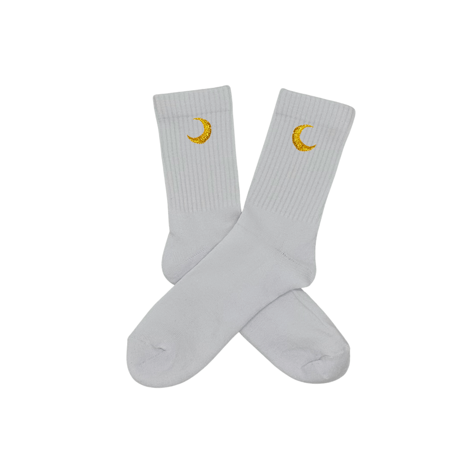 Chaussettes blanches hautes, 100% coton. Personnalisation des chaussettes grâce à des broderies. Il faut choisir parmi un choix de broderies dessinées à la main sur le thème de l’été sur la Côte d’Azur dans les Alpes Maritimes, 06. La broderie est présente sur le côté extérieur des chaussettes. Toutes les broderies sont faites à la commande selon la personnalisation choisie. Ici, il s’agit de la broderie lune, jaune.