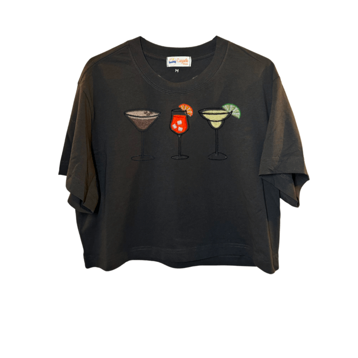 Crop top noir, manche courte, large, 100% coton. Personnalisation du débardeur grâce à des broderies. Il faut choisir parmi un choix de broderies dessinées à la main sur le thème de l’été sur la Côte d’Azur dans les Alpes Maritimes, 06. Il faut aussi choisir la position de la broderie entre à gauche côté cœur, à droite ou au milieu. Toutes les broderies sont faites à la commande selon la personnalisation choisie. Ici, il s’agit de la broderie 3 cocktails : espresso martini, Aperol spritz et margarita.