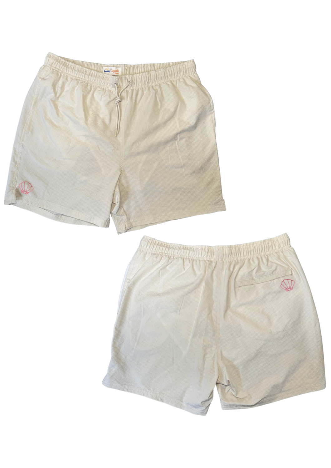 Maillot de plage pour homme couleur beige. Personnalisation du maillot grâce à des broderies. Il faut choisir parmi un choix de broderies dessinées à la main sur le thème de l’été sur la Côte d’Azur dans les Alpes Maritimes, 06. La broderie est brodée sur l’avant du maillot, jambe droite et sur la poche arrière jambe droite. Toutes les broderies sont faites à la commande selon la personnalisation choisie. Ici, il s’agit de la broderie coquillage rose.