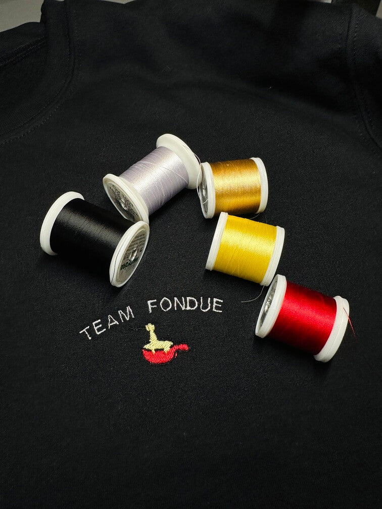 Sweatshirt tout doux hyper confortable loose avec broderie côté cœur et sur la manche droite personnalisation broderie team fondue.
Texte TEAM FONDUE avec un appareil à fondue rouge et du fromage coulant idée cadeau à offrir personnalisation broderie. Broderie côté cœur plus broderie sur la manche droite.