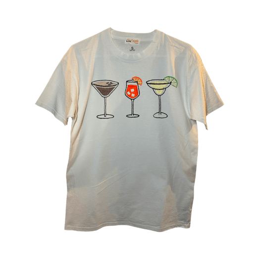T-shirt oversize blanc, 100% coton. Personnalisation du t-shirt grâce à des broderies. Il faut choisir parmi un choix de broderies dessinées à la main sur le thème de l’été sur la Côte d’Azur dans les Alpes Maritimes, 06. Il faut aussi choisir la position de la broderie entre à gauche côté cœur, à droite ou au milieu. Toutes les broderies sont faites à la commande selon la personnalisation choisie. Ici, il s’agit de la broderie 3 cocktails : espresso martini, Aperol spritz et margarita.
