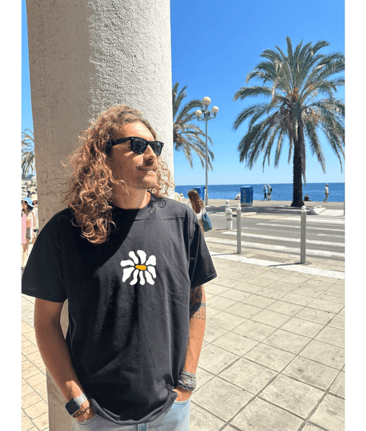 Mannequin, modèle homme t-shirt oversize noir 100% coton avec personnalisation flocage en DTF à l'avant au centre d'une fleur blanche.