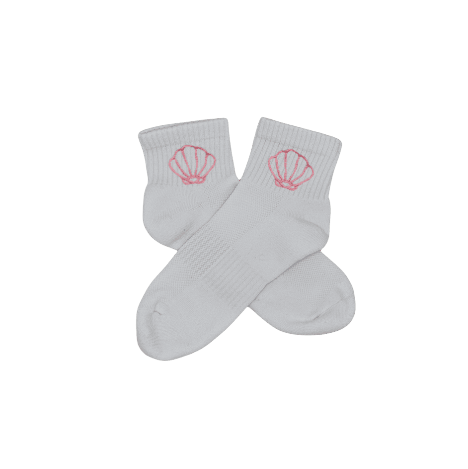 Chaussettes blanches courtes, 100% coton. Personnalisation des chaussettes grâce à des broderies. Il faut choisir parmi un choix de broderies dessinées à la main sur le thème de l’été sur la Côte d’Azur dans les Alpes Maritimes, 06. La broderie est présente sur le côté extérieur des chaussettes. Toutes les broderies sont faites à la commande selon la personnalisation choisie. Ici, il s’agit de la broderie coquillage, rose clair.