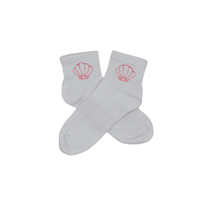 Chaussettes blanches courtes, 100% coton. Personnalisation des chaussettes grâce à des broderies. Il faut choisir parmi un choix de broderies dessinées à la main sur le thème de l’été sur la Côte d’Azur dans les Alpes Maritimes, 06. La broderie est présente sur le côté extérieur des chaussettes. Toutes les broderies sont faites à la commande selon la personnalisation choisie. Ici, il s’agit de la broderie coquillage, rose clair.