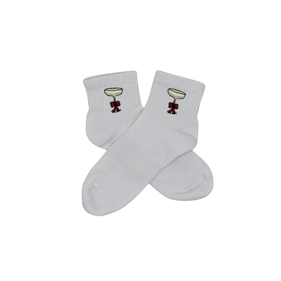 Chaussettes blanches courtes, 100% coton. Personnalisation des chaussettes grâce à des broderies. Il faut choisir parmi un choix de broderies dessinées à la main sur le thème de l’hiver, Noël, fêtes fin d’année, winter. La broderie est présente sur le côté extérieur des chaussettes. Toutes les broderies sont faites à la commande selon la personnalisation choisie. Ici, il s’agit de la broderie coupe de champagne
