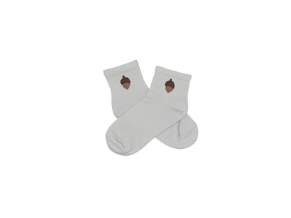 Chaussettes blanches courtes, 100% coton. Personnalisation des chaussettes grâce à des broderies. Il faut choisir parmi un choix de broderies dessinées à la main sur le thème de l’automne, saison automnale, Halloween, broderie cosy. La broderie est présente sur le côté extérieur des chaussettes. Toutes les broderies sont faites à la commande selon la personnalisation choisie. Ici, il s’agit de la broderie gland, marron.