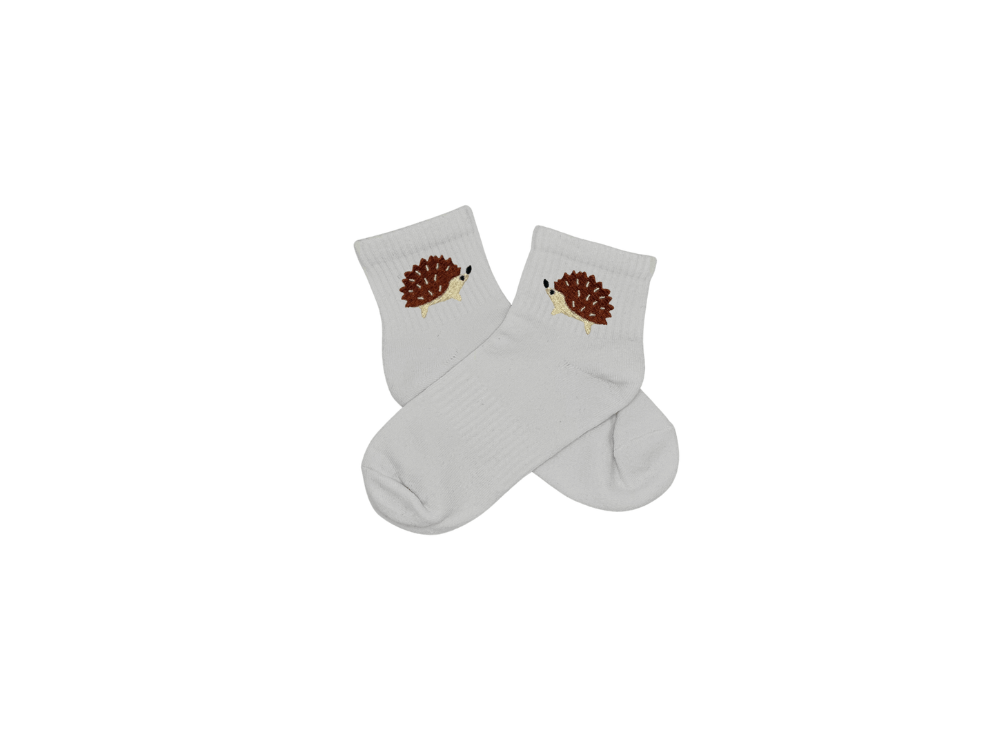 Chaussettes blanches courtes, 100% coton. Personnalisation des chaussettes grâce à des broderies. Il faut choisir parmi un choix de broderies dessinées à la main sur le thème de l’automne, saison automnale, Halloween, broderie cosy. La broderie est présente sur le côté extérieur des chaussettes. Toutes les broderies sont faites à la commande selon la personnalisation choisie. Ici, il s’agit de la broderie hérisson, marron, beige et noir.