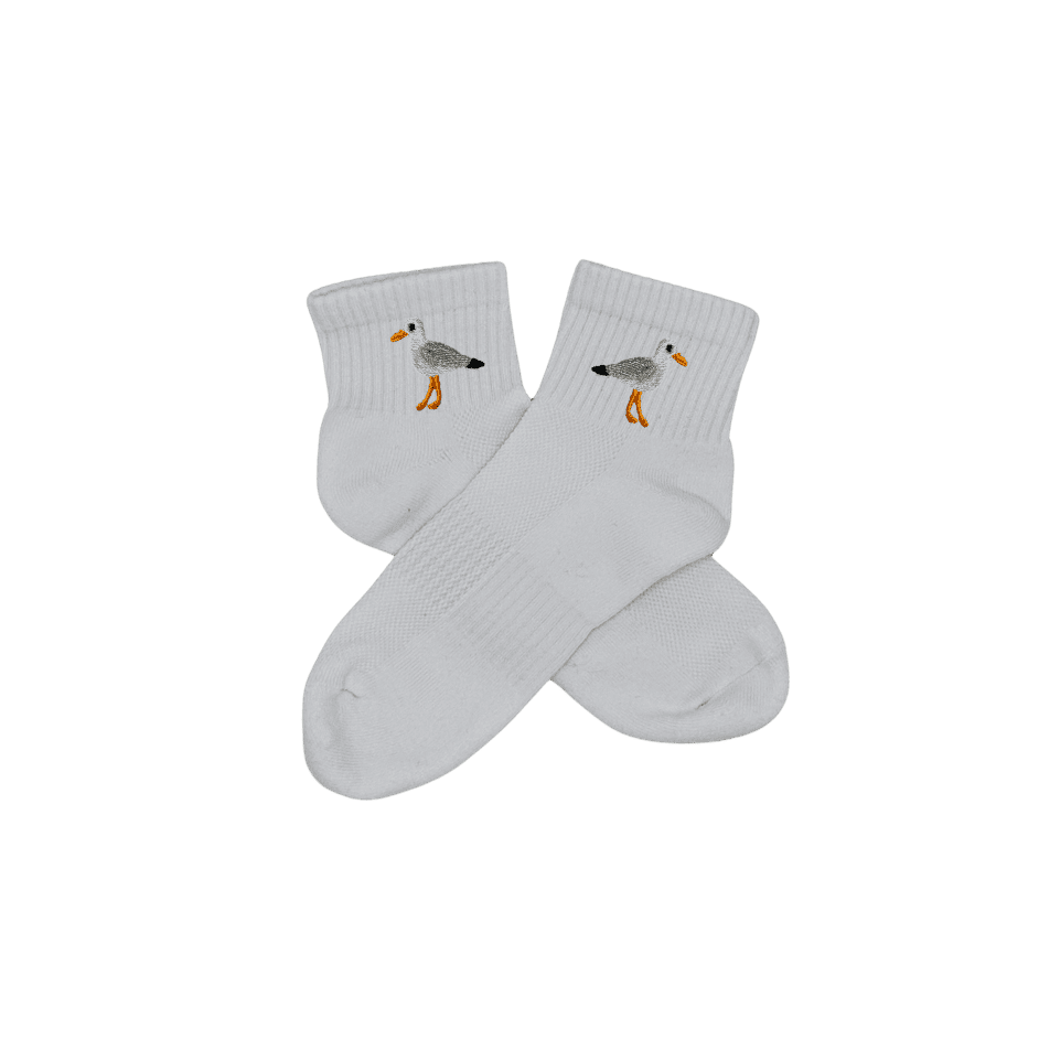 Chaussettes blanches courtes, 100% coton. Personnalisation des chaussettes grâce à des broderies. Il faut choisir parmi un choix de broderies dessinées à la main sur le thème de l’été sur la Côte d’Azur dans les Alpes Maritimes, 06. La broderie est présente sur le côté extérieur des chaussettes. Toutes les broderies sont faites à la commande selon la personnalisation choisie. Ici, il s’agit de la broderie mouette, blanc, gris, noir et orange.