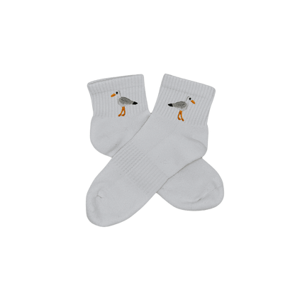 Chaussettes blanches courtes, 100% coton. Personnalisation des chaussettes grâce à des broderies. Il faut choisir parmi un choix de broderies dessinées à la main sur le thème de l’été sur la Côte d’Azur dans les Alpes Maritimes, 06. La broderie est présente sur le côté extérieur des chaussettes. Toutes les broderies sont faites à la commande selon la personnalisation choisie. Ici, il s’agit de la broderie mouette, blanc, gris, noir et orange.