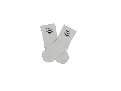 Chaussettes blanches courtes avec petits froufrous à l’extrémité, 100% coton. Personnalisation des chaussettes grâce à des broderies. Il faut choisir parmi un choix de broderies dessinées à la main sur le thème de l’automne, saison automnale, Halloween, broderie cosy. La broderie est présente sur le côté extérieur des chaussettes. Toutes les broderies sont faites à la commande selon la personnalisation choisie. Ici, il s’agit de la broderie 3 chauve-souris noires. 
