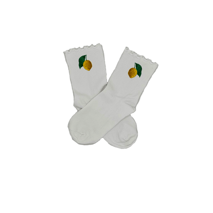 Chaussettes blanches courtes avec petits froufrous à l’extrémité, 100% coton. Personnalisation des chaussettes grâce à des broderies. Il faut choisir parmi un choix de broderies dessinées à la main sur le thème de l’été sur la Côte d’Azur dans les Alpes Maritimes, 06. La broderie est présente sur le côté extérieur des chaussettes. Toutes les broderies sont faites à la commande selon la personnalisation choisie. Ici, il s’agit de la broderie citron de Menton, jaune et vert. Emblème de la ville de Menton.