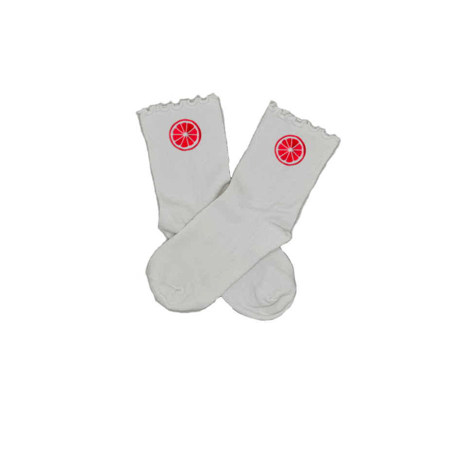 Chaussettes blanches courtes avec petits froufrous à l’extrémité, 100% coton. Personnalisation des chaussettes grâce à des broderies. Il faut choisir parmi un choix de broderies dessinées à la main sur le thème de l’été sur la Côte d’Azur dans les Alpes Maritimes, 06. La broderie est présente sur le côté extérieur des chaussettes. Toutes les broderies sont faites à la commande selon la personnalisation choisie. Ici, il s’agit de la broderie pomelo, pamplemousse, agrume, rose flashy. 