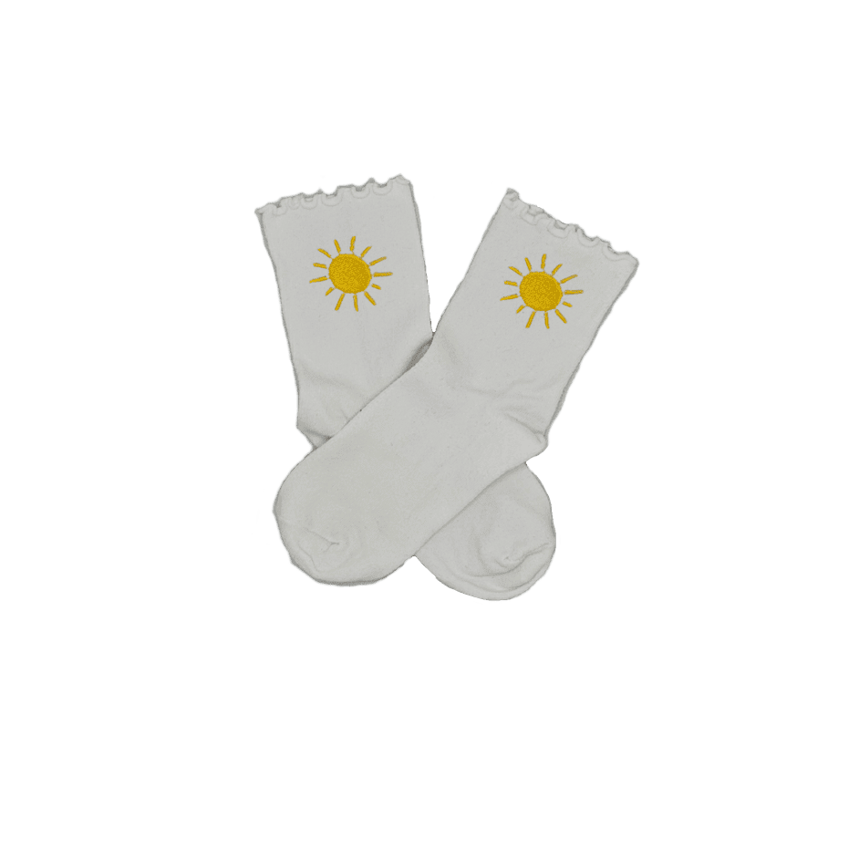 Chaussettes blanches courtes avec petits froufrous à l’extrémité, 100% coton. Personnalisation des chaussettes grâce à des broderies. Il faut choisir parmi un choix de broderies dessinées à la main sur le thème de l’été sur la Côte d’Azur dans les Alpes Maritimes, 06. La broderie est présente sur le côté extérieur des chaussettes. Toutes les broderies sont faites à la commande selon la personnalisation choisie. Ici, il s’agit de la broderie soleil jaune. 