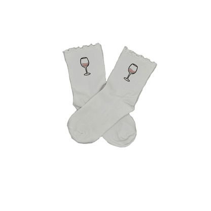 Chaussettes blanches courtes avec petits froufrous à l’extrémité, 100% coton. Personnalisation des chaussettes grâce à des broderies. Il faut choisir parmi un choix de broderies dessinées à la main sur le thème de l’été sur la Côte d’Azur dans les Alpes Maritimes, 06. La broderie est présente sur le côté extérieur des chaussettes. Toutes les broderies sont faites à la commande selon la personnalisation choisie. Ici, il s’agit de la broderie verre de vin rosé, rose clair et noir. 