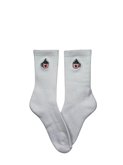 Chaussettes blanches hautes, 100% coton. Personnalisation des chaussettes grâce à des broderies. Il faut choisir parmi un choix de broderies dessinées à la main sur le thème de l’automne, saison automnale, Halloween, broderie cosy. La broderie est présente sur le côté extérieur des chaussettes. Toutes les broderies sont faites à la commande selon la personnalisation choisie. Ici, il s’agit de la broderie tasse de chocolat chaud rose avec un coeur rouge et marshmallow. 
