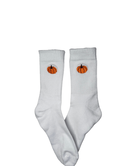 Chaussettes blanches hautes, 100% coton. Personnalisation des chaussettes grâce à des broderies. Il faut choisir parmi un choix de broderies dessinées à la main sur le thème de l’automne, saison automnale, Halloween, broderie cosy. La broderie est présente sur le côté extérieur des chaussettes. Toutes les broderies sont faites à la commande selon la personnalisation choisie. Ici, il s’agit de la broderie citrouille, orange.