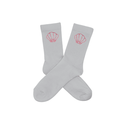 Chaussettes blanches hautes, 100% coton. Personnalisation des chaussettes grâce à des broderies. Il faut choisir parmi un choix de broderies dessinées à la main sur le thème de l’été sur la Côte d’Azur dans les Alpes Maritimes, 06. La broderie est présente sur le côté extérieur des chaussettes. Toutes les broderies sont faites à la commande selon la personnalisation choisie. Ici, il s’agit de la broderie coquillage rose clair.