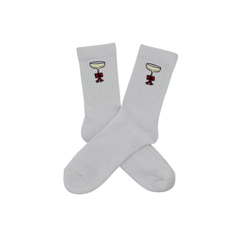 Chaussettes blanches hautes, 100% coton. Personnalisation des chaussettes grâce à des broderies. Il faut choisir parmi un choix de broderies dessinées à la main sur le thème de l’hiver, Noël, fêtes fin d’année, winter. La broderie est présente sur le côté extérieur des chaussettes. Toutes les broderies sont faites à la commande selon la personnalisation choisie. Ici, il s’agit de la broderie coupe de champagne 