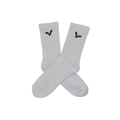 Chaussettes blanches hautes, 100% coton. Personnalisation des chaussettes grâce à des broderies. Il faut choisir parmi un choix de broderies dessinées à la main sur le thème de l’hiver, Noël, fêtes fin d’année, winter. La broderie est présente sur le côté extérieur des chaussettes. Toutes les broderies sont faites à la commande selon la personnalisation choisie. Ici, il s’agit de la broderie houx