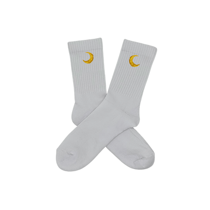 Chaussettes blanches hautes, 100% coton. Personnalisation des chaussettes grâce à des broderies. Il faut choisir parmi un choix de broderies dessinées à la main sur le thème de l’été sur la Côte d’Azur dans les Alpes Maritimes, 06. La broderie est présente sur le côté extérieur des chaussettes. Toutes les broderies sont faites à la commande selon la personnalisation choisie. Ici, il s’agit de la broderie lune, jaune.