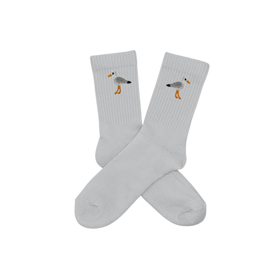 Chaussettes blanches hautes, 100% coton. Personnalisation des chaussettes grâce à des broderies. Il faut choisir parmi un choix de broderies dessinées à la main sur le thème de l’été sur la Côte d’Azur dans les Alpes Maritimes, 06. La broderie est présente sur le côté extérieur des chaussettes. Toutes les broderies sont faites à la commande selon la personnalisation choisie. Ici, il s’agit de la broderie mouette, blanc, gris, noir et orange.