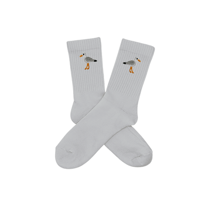 Chaussettes blanches hautes, 100% coton. Personnalisation des chaussettes grâce à des broderies. Il faut choisir parmi un choix de broderies dessinées à la main sur le thème de l’été sur la Côte d’Azur dans les Alpes Maritimes, 06. La broderie est présente sur le côté extérieur des chaussettes. Toutes les broderies sont faites à la commande selon la personnalisation choisie. Ici, il s’agit de la broderie mouette, blanc, gris, noir et orange.