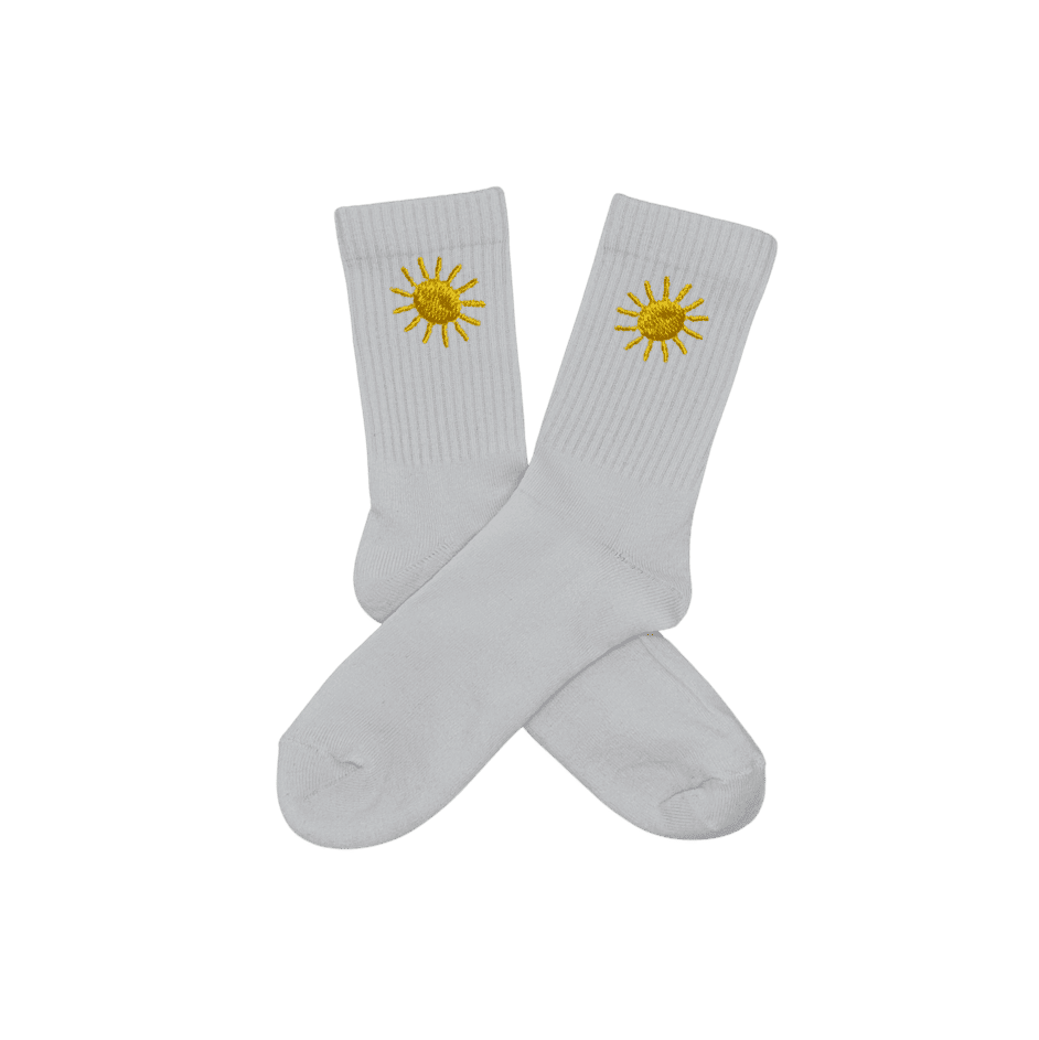 Chaussettes blanches hautes, 100% coton. Personnalisation des chaussettes grâce à des broderies. Il faut choisir parmi un choix de broderies dessinées à la main sur le thème de l’été sur la Côte d’Azur dans les Alpes Maritimes, 06. La broderie est présente sur le côté extérieur des chaussettes. Toutes les broderies sont faites à la commande selon la personnalisation choisie. Ici, il s’agit de la broderie soleil, jaune. 