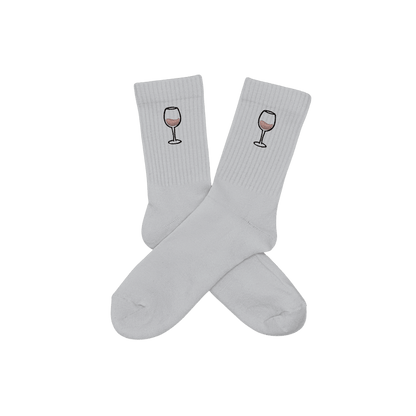 Chaussettes blanches hautes, 100% coton. Personnalisation des chaussettes grâce à des broderies. Il faut choisir parmi un choix de broderies dessinées à la main sur le thème de l’été sur la Côte d’Azur dans les Alpes Maritimes, 06. La broderie est présente sur le côté extérieur des chaussettes. Toutes les broderies sont faites à la commande selon la personnalisation choisie. Ici, il s’agit de la broderie verre de vin rosé, rose clair et noir.