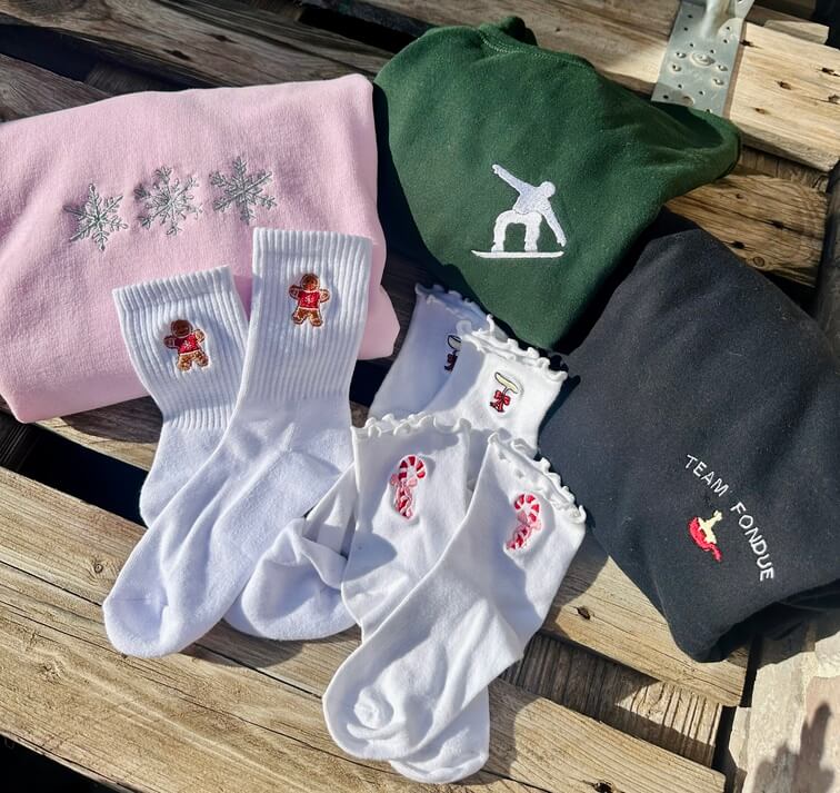Sweatshirt rose avec broderie de 3 flocons argenté, fil métallique, brillant.
Sweatshirt vert forêt avec broderie d'un snowboard blanc. 
Sweatshirt noir avec broderie team fondue fromage fondu.
Chaussettes brodées bonhomme en pain d'épices, coupe de champagne et sucre d'orge.