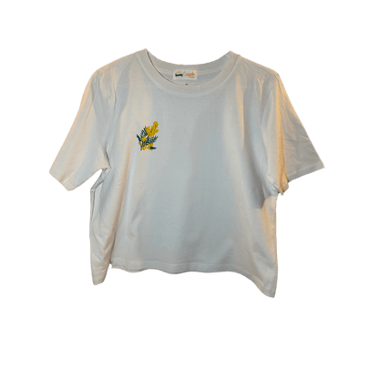 Crop top blanc, manche courte, large, 100% coton. Personnalisation du débardeur grâce à des broderies. Il faut choisir parmi un choix de broderies dessinées à la main sur le thème de l’été sur la Côte d’Azur dans les Alpes Maritimes, 06. Il faut aussi choisir la position de la broderie entre à gauche côté cœur, à droite ou au milieu. Toutes les broderies sont faites à la commande selon la personnalisation choisie. Ici, il s’agit de la broderie mimosa, jaune et vert foncé. 