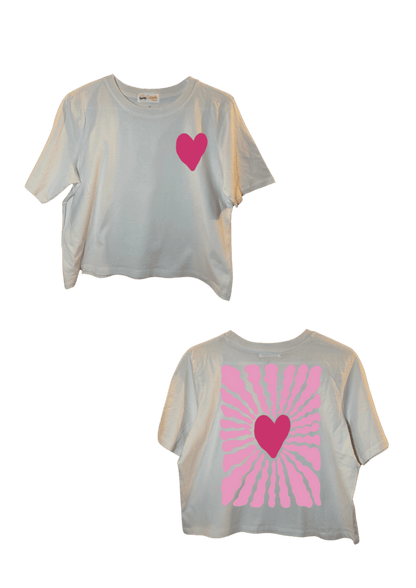 Crop top blanc court, manche courte, 100% coton. Personnalisation du crop top grâce à une technique de flocage, le DTF, pour une meilleure qualité d’impression et de tenue. La personnalisation est floquée à l’avant au niveau du cœur, en haut à gauche et à l’arrière en grand dans le dos. Ici, il s’agit de la personnalisation de DTF cœur rose. 