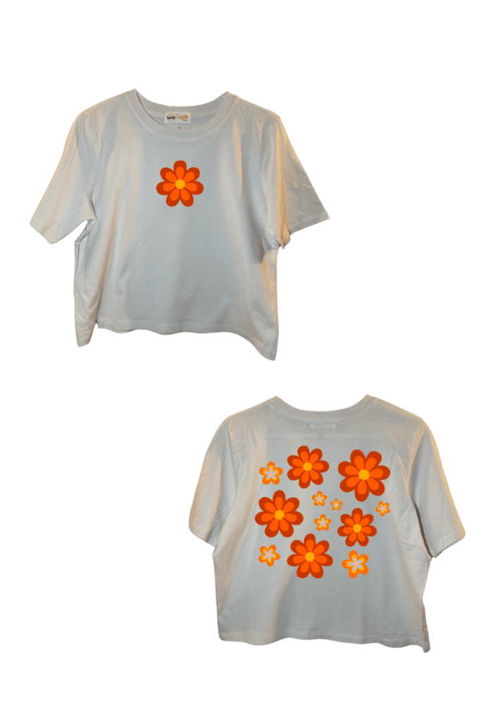 Crop top blanc court, manche courte, 100% coton. Personnalisation du crop top grâce à une technique de flocage, le DTF, pour une meilleure qualité d’impression et de tenue. La personnalisation est floquée à l’avant au niveau du cœur, en haut à gauche et à l’arrière en grand dans le dos. Ici, il s’agit de la personnalisation de DTF fleur orange style années 70.