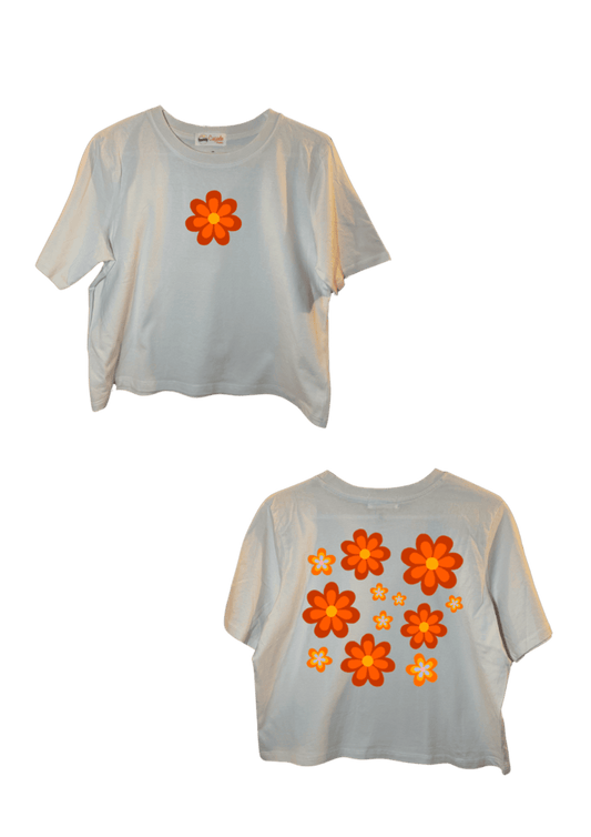 Crop top blanc court, manche courte, 100% coton. Personnalisation du crop top grâce à une technique de flocage, le DTF, pour une meilleure qualité d’impression et de tenue. La personnalisation est floquée à l’avant au niveau du cœur, en haut à gauche et à l’arrière en grand dans le dos. Ici, il s’agit de la personnalisation de DTF fleur orange style années 70.