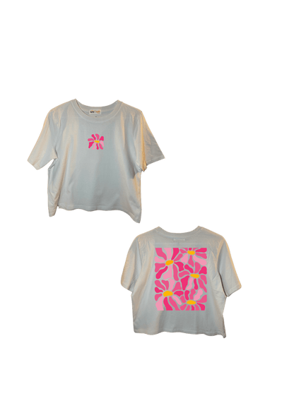 Crop top blanc court, manche courte, 100% coton. Personnalisation du crop top grâce à une technique de flocage, le DTF, pour une meilleure qualité d’impression et de tenue. La personnalisation est floquée à l’avant au milieu en haut et à l’arrière en grand dans le dos. Ici, il s’agit de la personnalisation de DTF fleur rose. 