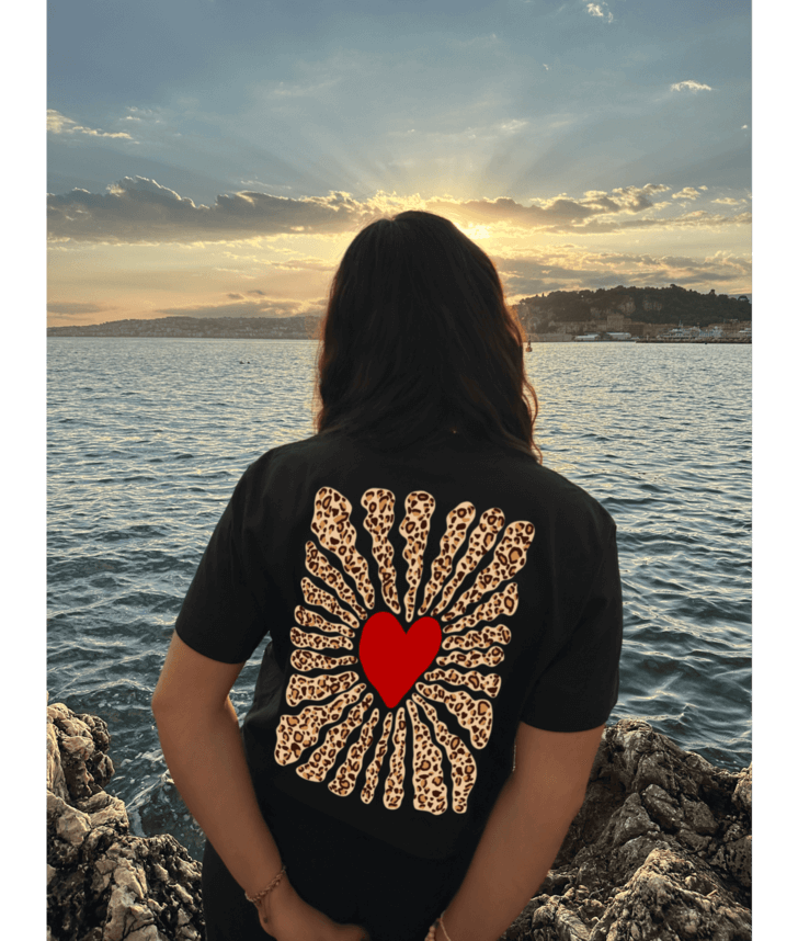Le dessin léopard de ce crop top évoque un esprit sauvage, audacieux et libre. Inspiré des motifs emblématiques des années 60 et 70, ce design réinterprète l'énergie vibrante et la confiance de cette époque. Le cœur, entouré de rayons aux imprimés léopard, symbolise l'amour libre et indomptable, une célébration visuelle de l'authenticité et de l'individualité. Un motif qui parle à ceux qui osent exprimer leur côté sauvage avec élégance.