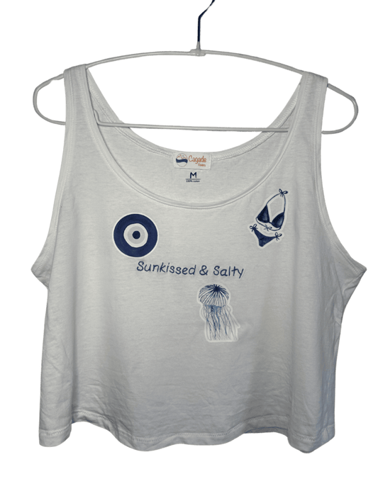 Débardeur blanc court, crop top, 100% coton. Personnalisation du débardeur grâce à des broderies et du flocage DTF. Toutes les broderies sont faites à la commande. Ici, il s’agit de la broderie écriture "sunkissed & salty". et flocage DTF bleu de l'oeil de sainte lucie d'un maillot de bain femme bleu et d'une méduse bleue.