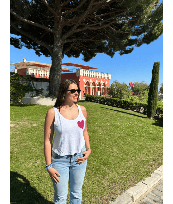 Mannequin femme portant un débardeur blanc avec personnalisation flocage DTF coeur rose. Chateau Nice 06 été soleil