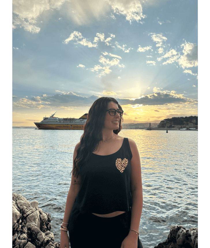 Mannequin modèle femme portant un débardeur noir court en coton avec personnalisation flocage DTF coeur léopard. Plage mer été coucher de soleil lunettes Nice 06