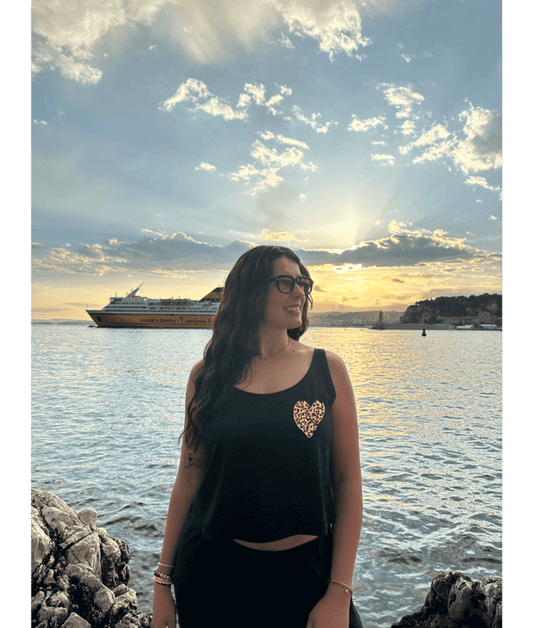 Mannequin modèle femme portant un débardeur noir court en coton avec personnalisation flocage DTF coeur léopard. Plage mer été coucher de soleil lunettes Nice 06