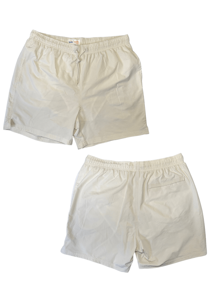 Maillot de plage pour homme couleur beige. Personnalisation du maillot grâce à des broderies. Il faut choisir parmi un choix de broderies dessinées à la main sur le thème de l’été sur la Côte d’Azur dans les Alpes Maritimes, 06. La broderie est brodée sur l’avant du maillot, jambe droite et sur la poche arrière jambe droite. Toutes les broderies sont faites à la commande selon la personnalisation choisie. Maillot présentation sans broderie.