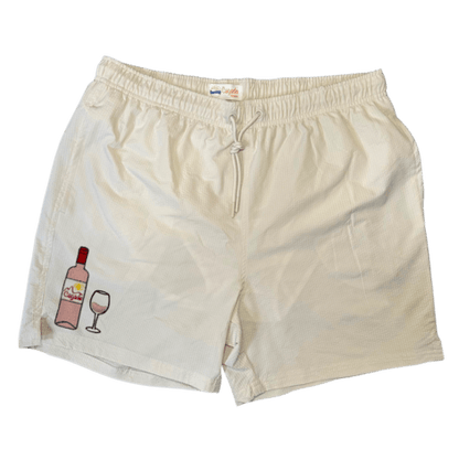 Maillot de plage pour homme couleur beige. Personnalisation du maillot grâce à des broderies. Il faut choisir parmi un choix de broderies dessinées à la main sur le thème de l’été sur la Côte d’Azur dans les Alpes Maritimes, 06. La broderie est brodée sur l’avant du maillot, jambe droite. Toutes les broderies sont faites à la commande selon la personnalisation choisie. Ici, il s’agit de la broderie bouteille de vin rosé et verre de vin rosé.