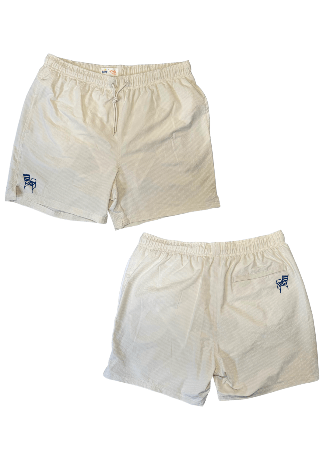 Maillot de plage pour homme couleur beige. Personnalisation du maillot grâce à des broderies. Il faut choisir parmi un choix de broderies dessinées à la main sur le thème de l’été sur la Côte d’Azur dans les Alpes Maritimes, 06. La broderie est brodée sur l’avant du maillot, jambe droite et sur la poche arrière jambe droite. Toutes les broderies sont faites à la commande selon la personnalisation choisie. Ici, il s’agit de la broderie chaise bleue, emblème de la ville de Nice, 06.