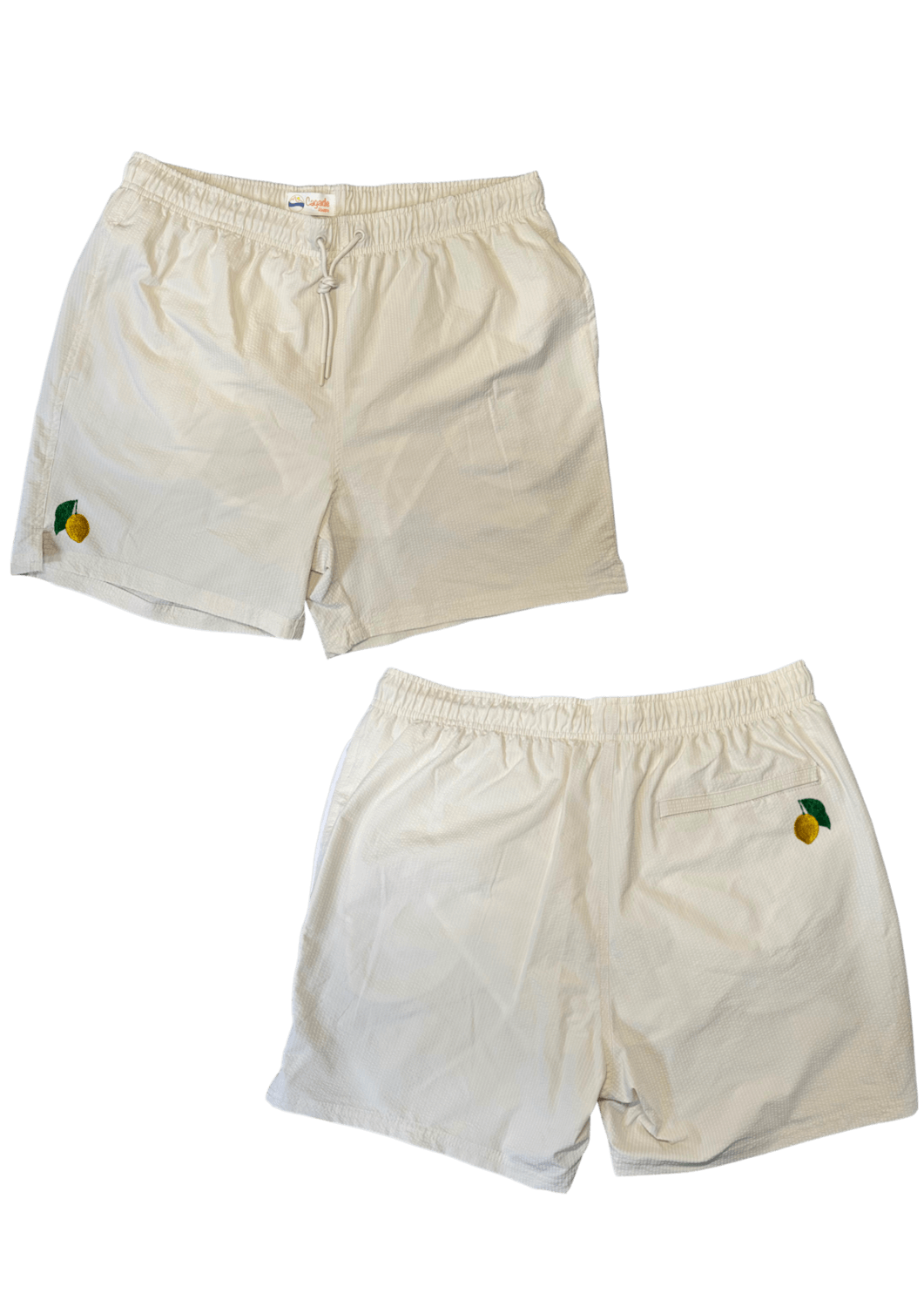 Maillot de plage pour homme couleur beige. Personnalisation du maillot grâce à des broderies. Il faut choisir parmi un choix de broderies dessinées à la main sur le thème de l’été sur la Côte d’Azur dans les Alpes Maritimes, 06. La broderie est brodée sur l’avant du maillot, jambe droite et sur la poche arrière jambe droite. Toutes les broderies sont faites à la commande selon la personnalisation choisie. Ici, il s’agit de la broderie citron de Menton, emblème de la ville de Menton, 06.