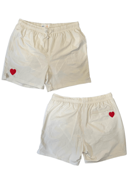 Maillot de plage pour homme couleur beige. Personnalisation du maillot grâce à des broderies. Il faut choisir parmi un choix de broderies dessinées à la main sur le thème de l’été sur la Côte d’Azur dans les Alpes Maritimes, 06. La broderie est brodée sur l’avant du maillot, jambe droite et sur la poche arrière jambe droite. Toutes les broderies sont faites à la commande selon la personnalisation choisie. Ici, il s’agit de la broderie coeur rouge