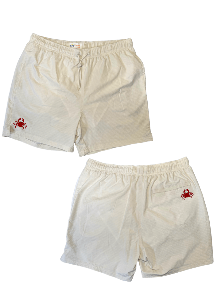 Maillot de plage pour homme couleur beige. Personnalisation du maillot grâce à des broderies. Il faut choisir parmi un choix de broderies dessinées à la main sur le thème de l’été sur la Côte d’Azur dans les Alpes Maritimes, 06. La broderie est brodée sur l’avant du maillot, jambe droite et sur la poche arrière jambe droite. Toutes les broderies sont faites à la commande selon la personnalisation choisie. Ici, il s’agit de la broderie crabe, rouge.