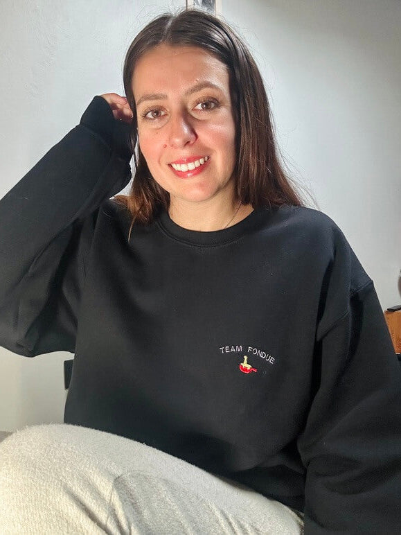 Sweatshirt tout doux hyper confortable loose avec broderie côté cœur et sur la manche droite personnalisation broderie team fondue. 
Texte TEAM FONDUE avec un appareil à fondue rouge et du fromage coulant idée cadeau à offrir personnalisation broderie. Broderie côté cœur plus broderie sur la manche droite. 