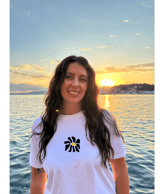 Modèle femme portant un t-shirt oversize blanc 100% coton avec une personnalisation de flocage DTF à l'avant au milieu d'une fleur noir.