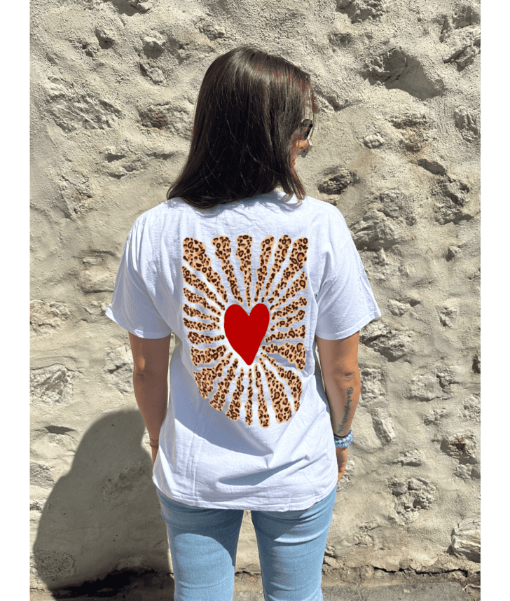 T-shirt oversize blanc, manche courte, 100% coton. Personnalisation du t-shirt grâce à une technique de flocage, le DTF, pour une meilleure qualité d’impression et de tenue. La personnalisation est floquée à l’avant au milieu en haut et à l’arrière en grand dans le dos. Ici, il s’agit de la personnalisation de DTF coeur léopard à l'avant et coeur rouge avec soleil léopard à l'arrière.