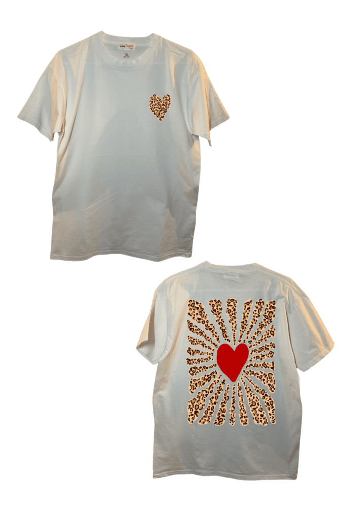 T-shirt oversize blanc, manche courte, 100% coton. Personnalisation du t-shirt grâce à une technique de flocage, le DTF, pour une meilleure qualité d’impression et de tenue. La personnalisation est floquée à l’avant au milieu en haut et à l’arrière en grand dans le dos. Ici, il s’agit de la personnalisation de DTF coeur léopard à l'avant et coeur rouge avec soleil léopard à l'arrière.