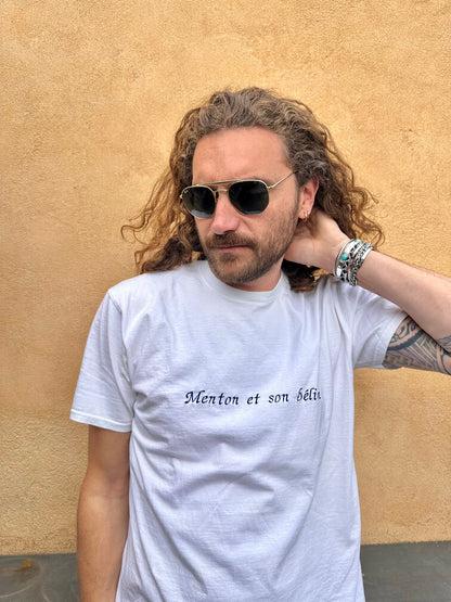 T-shirt oversize blanc, 100% coton. Personnalisation du t-shirt grâce à des broderies. Il faut choisir parmi un choix de broderies dessinées à la main sur le thème de l’été sur la Côte d’Azur dans les Alpes Maritimes, 06. Toutes les broderies sont faites à la commande selon la personnalisation choisie. Ici, il s’agit de la broderie "Menton et son bélin". Phrase typique de Menton Nice idée cadeau régional.